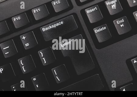 Simple modern black dark grey matte computer keyboard keys detail, background top view, enter key from above, nobody. Desktop PC keyboard minimal mode Stock Photo