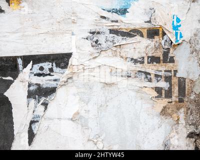 Lots of torn damaged paper posters, adverts, scraped off advertisements on a building wall, abstract creative background texture, old ads rough grunge Stock Photo