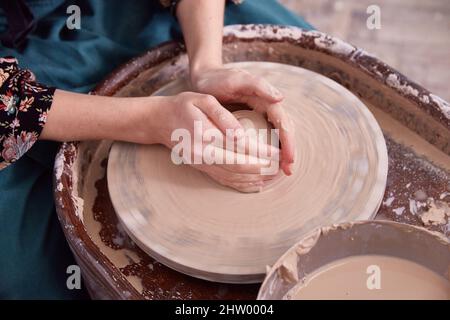 Beautiful women's hands make ceramic dishes on a potter's wheel. Stock Photo