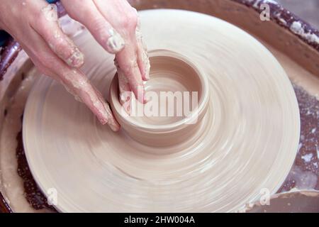 Beautiful women's hands make ceramic dishes on a spinning potter's wheel. soft focus Stock Photo