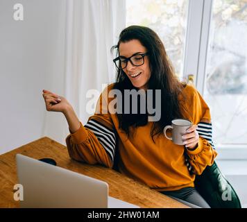 Smiling woman in her home office have video call on computer. Female freelance employee and work remote form house. Mom blogger using internet shop. Stock Photo