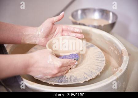 Beautiful women's hands make ceramic dishes on a spinning potter's wheel. soft focus Stock Photo