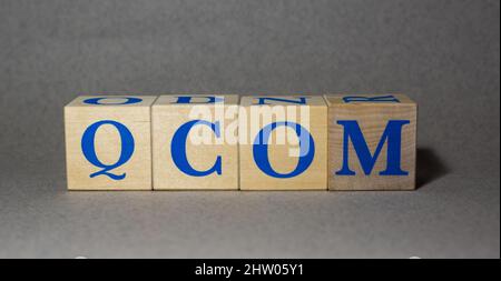 January 19, 2022. New York, USA. Exchange Ticker symbol of QUALCOMM Incorporated QCOM, made of wooden cubes, on a gray background. Stock Photo