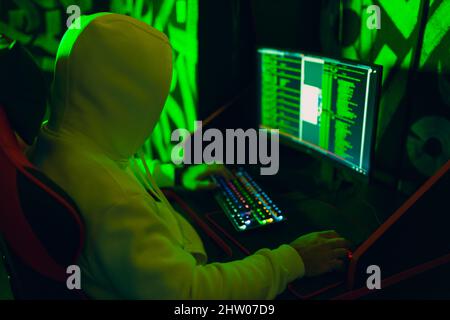 Hacker in hoodie working hacks code site on personal computer. War and cyber attack concept Stock Photo