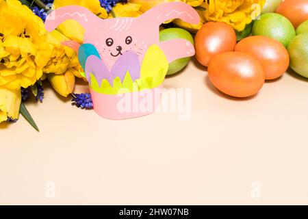 Pink paper Easter bunny and colorful eggs on a beige background with space for text. Stock Photo