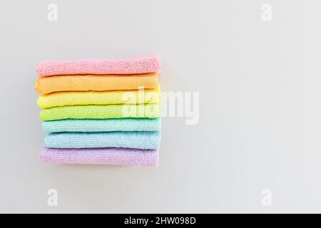 New folded microfiber cloth for cleaning in seven rainbow colors on gray background. Cleaning micro fabric towels for dusting and polishing. Domestic household cleaning service concept. Top view, copy space Stock Photo
