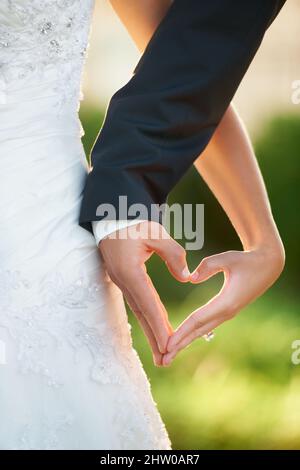 The shape of love. Cropped image of a newlywed couple making a heart with their hands. Stock Photo