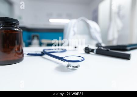 Selective focus on medical stethoscope standing on table ready for disease consultation. Empty doctor office with nobody in it equipped with professional examination tools. Medicine concept Stock Photo