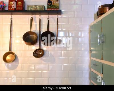 Kitchen utensils hanging from shelves in tyhe kitchen of a restaurant Stock Photo