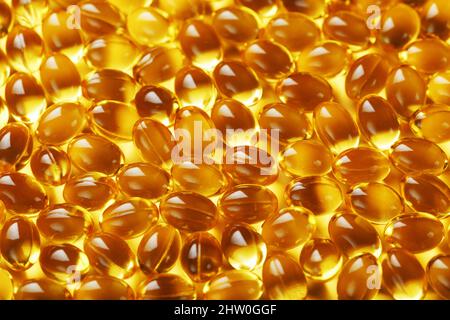 The texture of the capsules in the shell with liquid vitamin D3 in full screen. Gold capsules with a dietary supplement for joints teeth and bones. Stock Photo