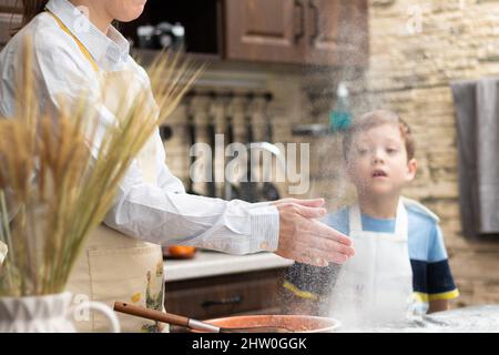 Mom and son in aprons play with flour while cooking at home in the kitchen  against the background of kitchen utensils. Selective focus. Portrait. Clos  Stock Photo - Alamy