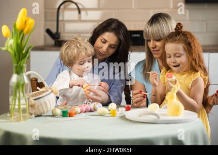 Mothers with their children paint eggs in preparation for the Easter holidays Stock Photo