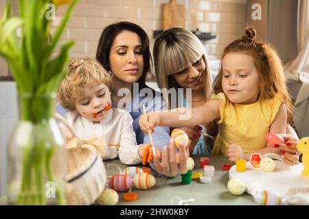 Happy mothers and their children decorating Easter eggs Stock Photo
