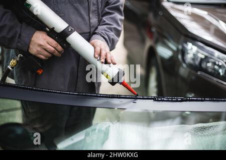 auto repairman sealing car windshield Stock Photo