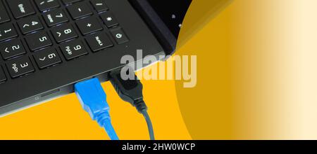 Connecting computers and laptops to the Internet using USB cables. Yellow background with place for text. The laptop connects the USB-C cable adapter Stock Photo