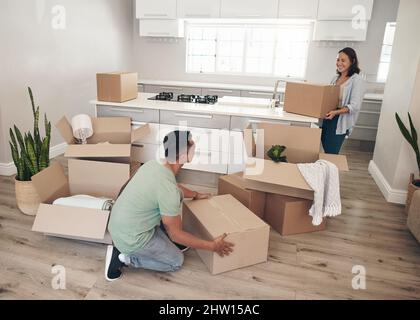 Do you know where you want this box yet. Shot of a young couple moving into their new home. Stock Photo