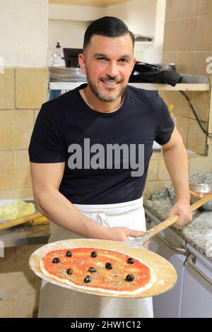 France, Bouches du Rhone, Marseille, Panier district, Chez Etienne pizzeria, chef Pascal Cassaro preparing an anchovy pizza before cooking it in a wood fired oven Stock Photo