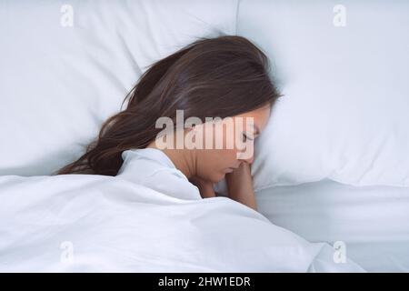 Depressed woman lying in the bed. Woman filling bad and suffering from depression Stock Photo