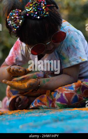 Colorful Holi Theme - Portrait Of Cute Indian Kid Wearing Round Colored Shades And Pinted In Holi Color Powder Called Rang Gulal Stock Photo