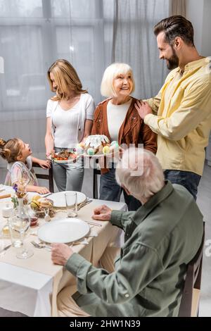 senior woman holding easter cake while serving table for family easter dinner,stock image Stock Photo