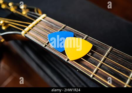 Blue and yellow guitar picks on an acoustic guitar Stock Photo