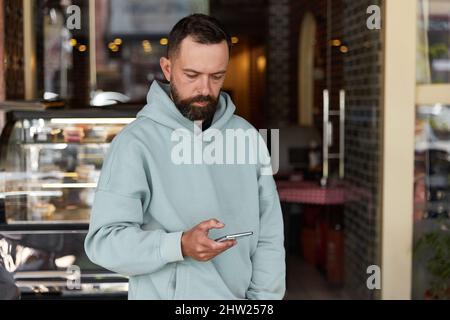 Bearded man in casual clothes using his smartphone Stock Photo
