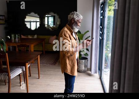 Side view of bearded senior african american man text messaging on smartphone at home Stock Photo