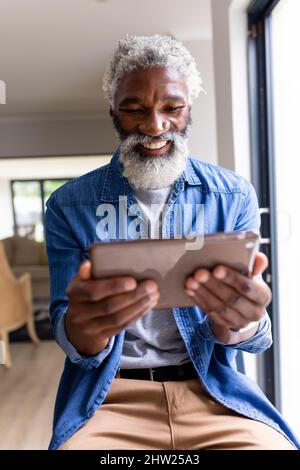 Smiling african american man with white beard using tablet pc at home Stock Photo