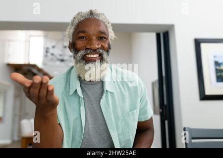 Portrait of smiling african american senior man gesturing while sitting in living room at home Stock Photo