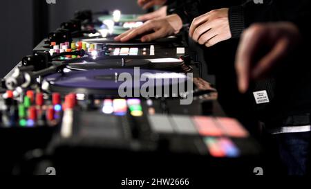 Close up of three men DJs playing electronic party music on vinyl cd usb player in the studio. Art. Side view of male hands and turntable controlling Stock Photo