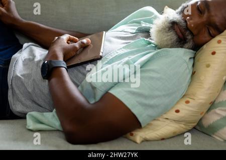 Tired senior african american man sleeping with digital tablet on sofa in living room at home Stock Photo