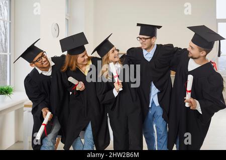 Multiracial group of happy university graduates hugging and having fun in classroom Stock Photo