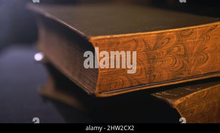 Vintage books, close-up. Pile of old books lying on the table in the dark room. Stock Photo