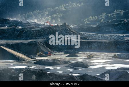 Quarry with working excavators, loaders and mining trucks and piles of crushed stone, industrial landscape Stock Photo