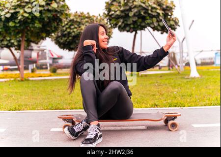 Beautiful skater girl taking a selfie at park