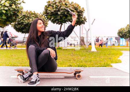 Beautiful skater girl taking a selfie at park