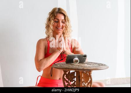 Fitness coach teaching yoga online to group of people. People practicing yoga with trainer via video conference Stock Photo