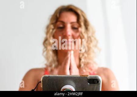 Fitness coach teaching yoga online to group of people. People practicing yoga with trainer via video conference Stock Photo