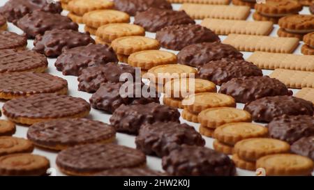 Close-up photo of beautiful chocolate glazed cookies, round filled and rectangular crackers stacked in rows in a beautiful pattern Stock Photo