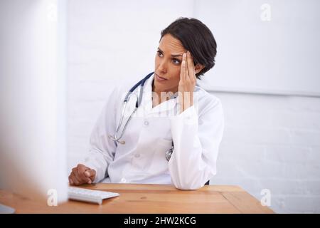So much to remember.... Portrait of a young female doctor working at her computer. Stock Photo