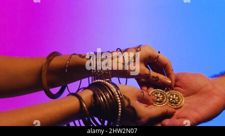 Indian woman with earrings in hand. Stock. Woman gives a man her jewelry, a gift as a sign of friendship. Stock Photo