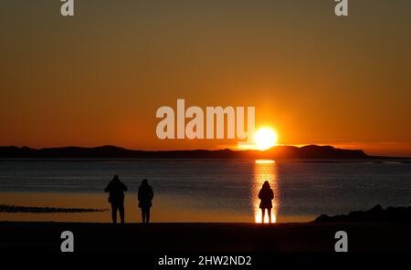 03 March 2022, Schleswig-Holstein, Föhr: Island visitors watch the sunset on the beach of Utersum on the North Sea island of Föhr. Photo: Christian Charisius/dpa Stock Photo