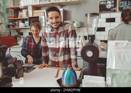 Positive photo of male barista standing behind counter Stock Photo