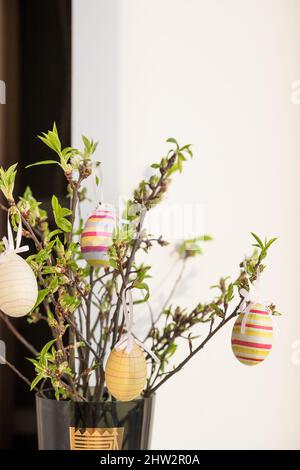 Easter composition. tree branches with green small leaves and colorful Easter eggs on blurred background.Concept interior design for spring holidays Stock Photo