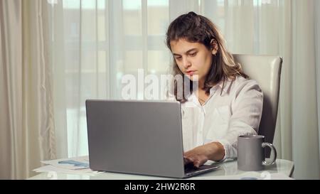 Disabled woman freelancer drinks tea working on computer Stock Photo