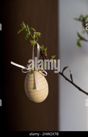Easter composition. tree branches with green small leaves and colorful Easter eggs on blurred background.Concept interior design for spring holidays Stock Photo