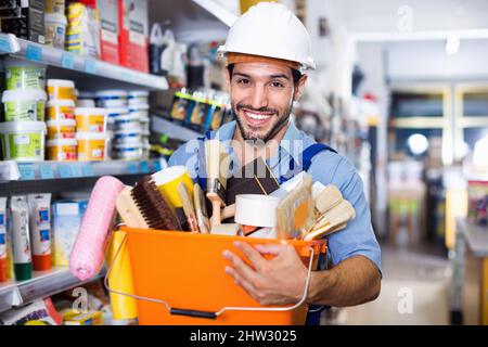 Workman holding basket with picked tools in paint store Stock Photo