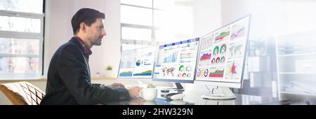 Man Advisor Using Multiple Computer Monitors With Finance Charts Stock Photo