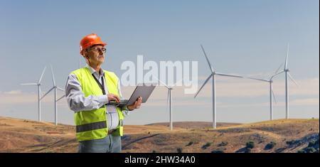 Engineer working with a laptop computer on a wind turbine farm Stock Photo