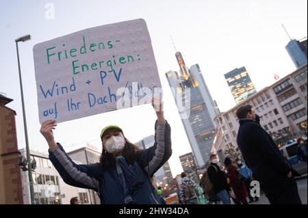 03 March 2022, Hessen, Frankfurt/Main: A participant holds up a sign at a Fridays for Future demonstration against the war in Ukraine that reads 'Peace Energies: Wind PV on your roof/balcony.' The Fridays for Future organization is taking to the streets around the world this Thursday to express solidarity with Ukraine and to protest Russia's attack on the country. Photo: Sebastian Christoph Gollnow/dpa Stock Photo